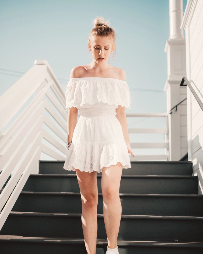 Smiling woman in a white summer dress on an outdoor staircase